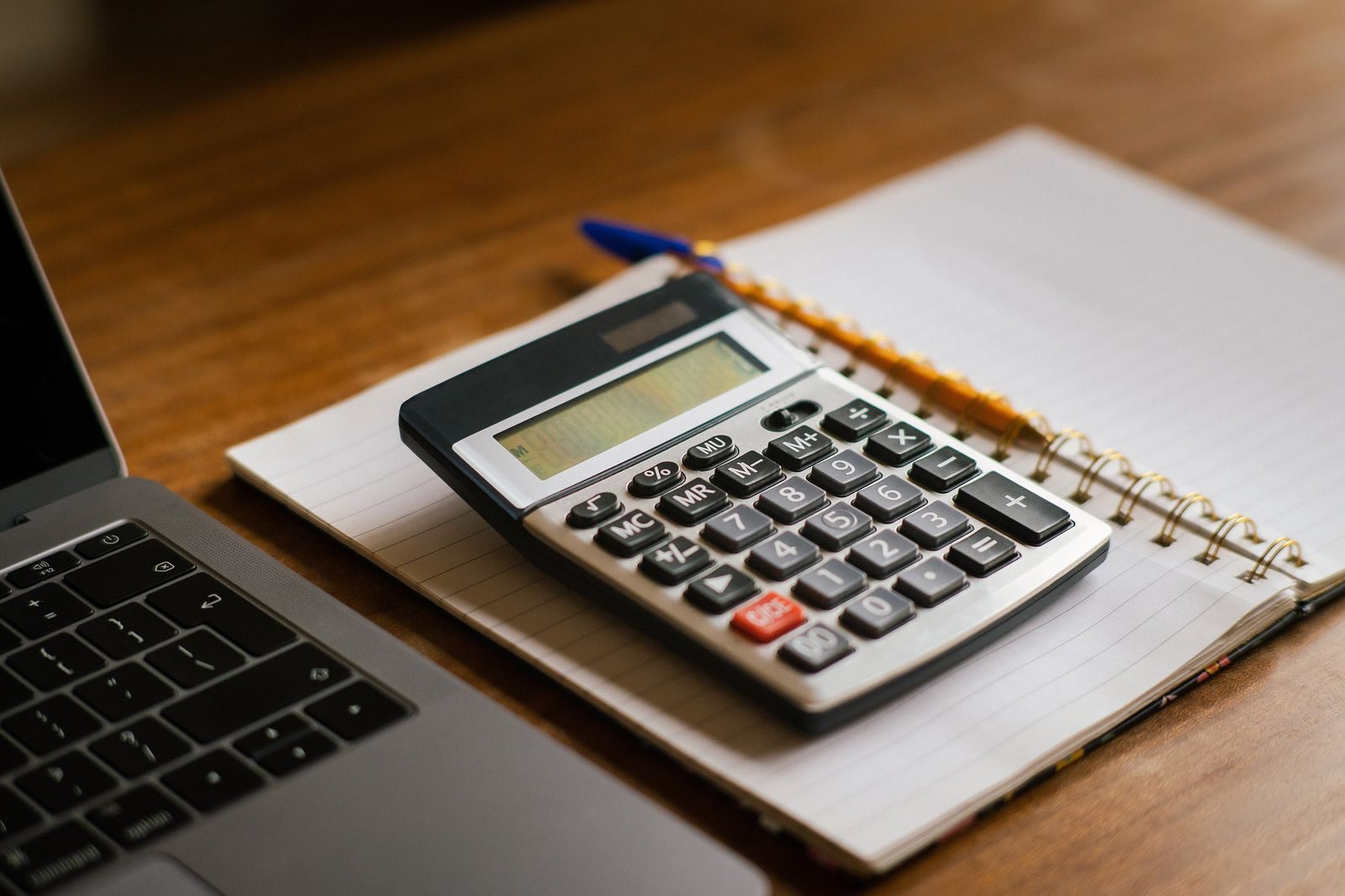 A calculator on a notebook beside an open laptop, ready for a cruise budget calculator session