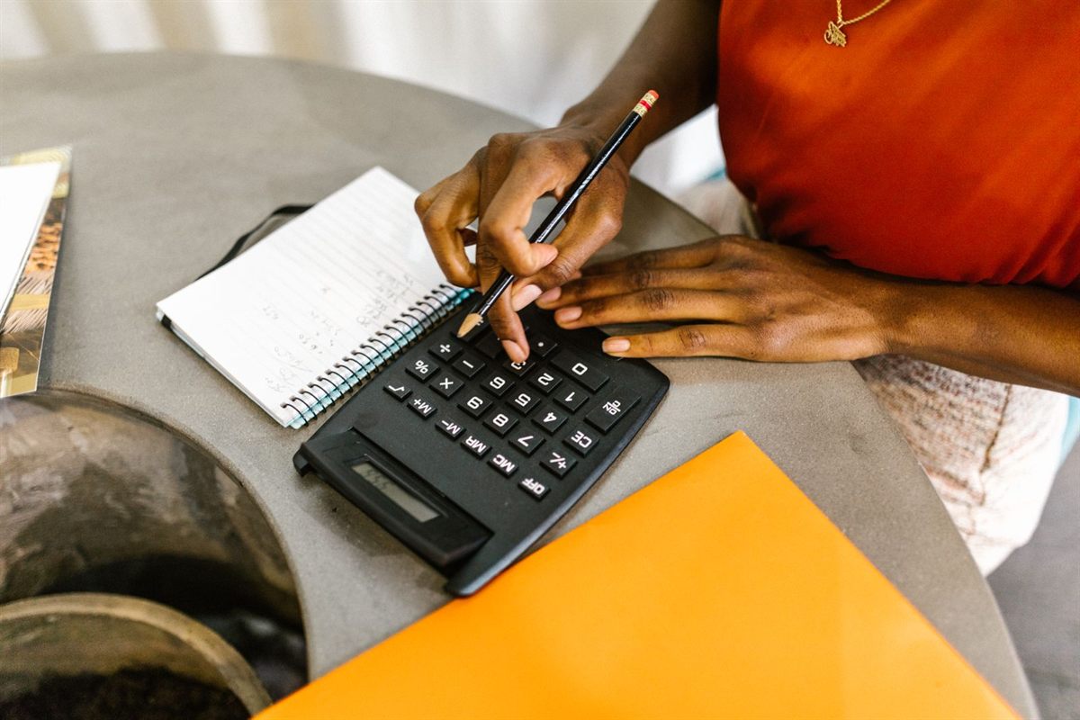 A woman using a calculator and notepad to plan a budget