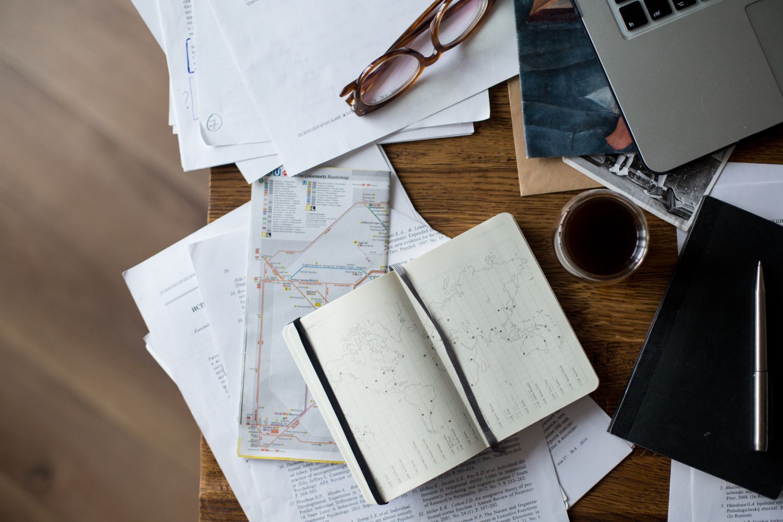 A desk covered with maps, an open notebook, glasses and coffee, laid out like a cruise planner template