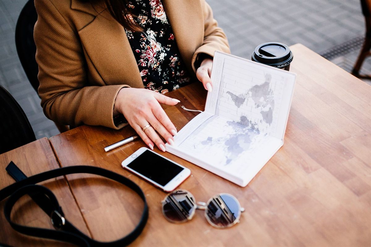 A woman reading a travel planner with a map at a café table